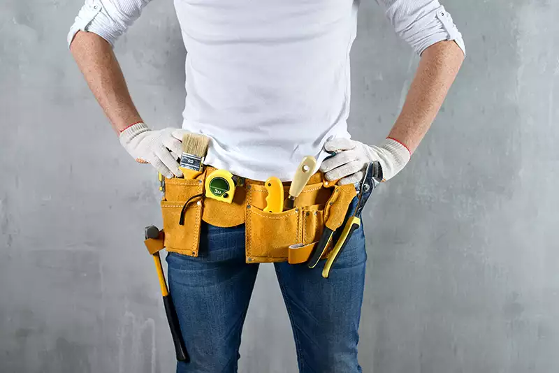 Person with hands on hips with tool-belt on