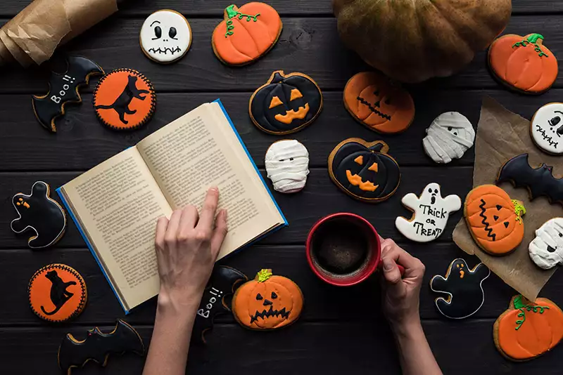Book in front of pile of halloween themed cookies