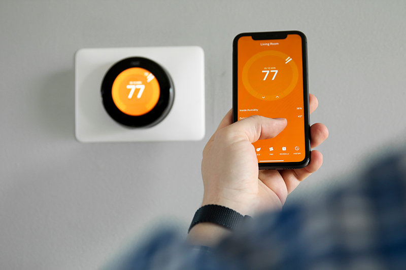 Man adjusting thermostat temperature from his phone.