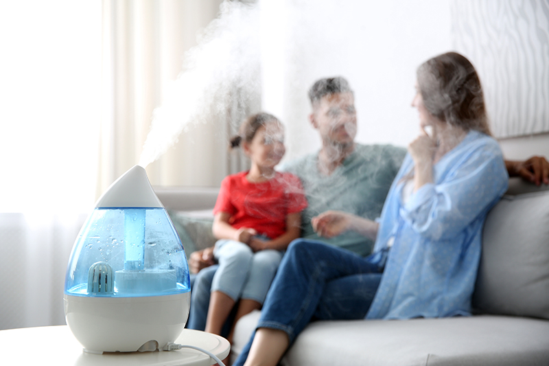 Humidifier on a coffee table with family sitting on the couch in the background.