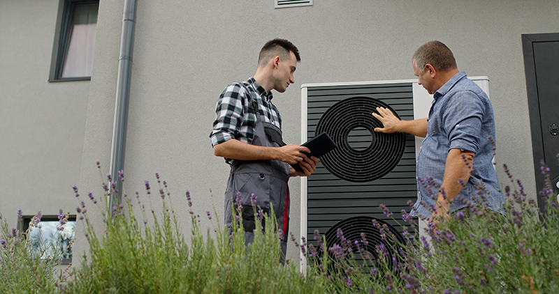 Homeowner and Technician looking at heat pump.