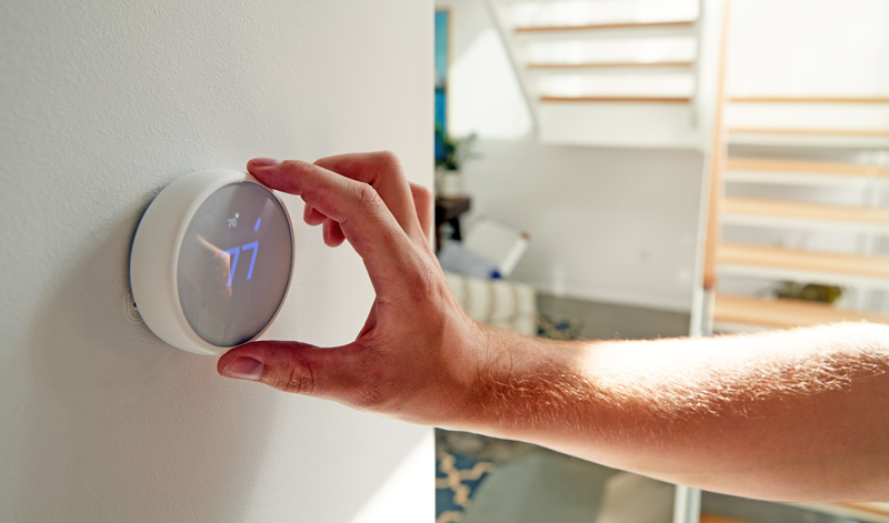 Individual adjusting the temperature on their smart thermostat.