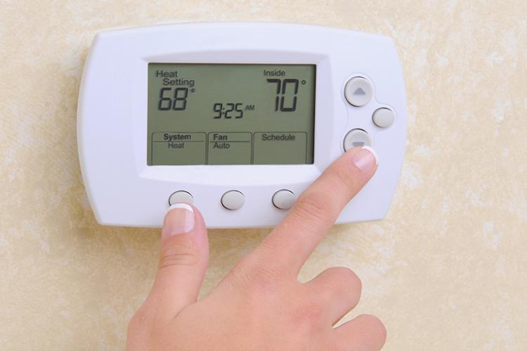 Close up of hand and programmable thermostat