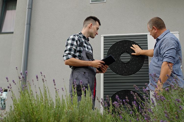 Homeowner and Technician looking at heat pump.