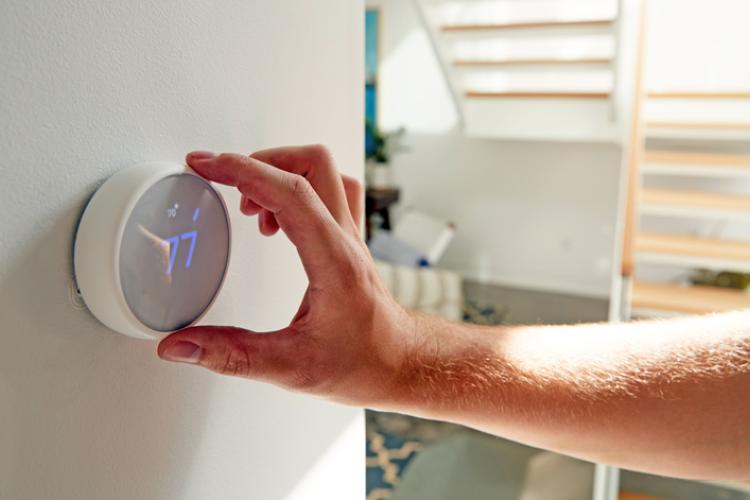 Individual adjusting the temperature on their smart thermostat.